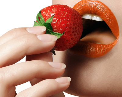 Eine attraktive Frau isst verführerisch eine Erdbeere